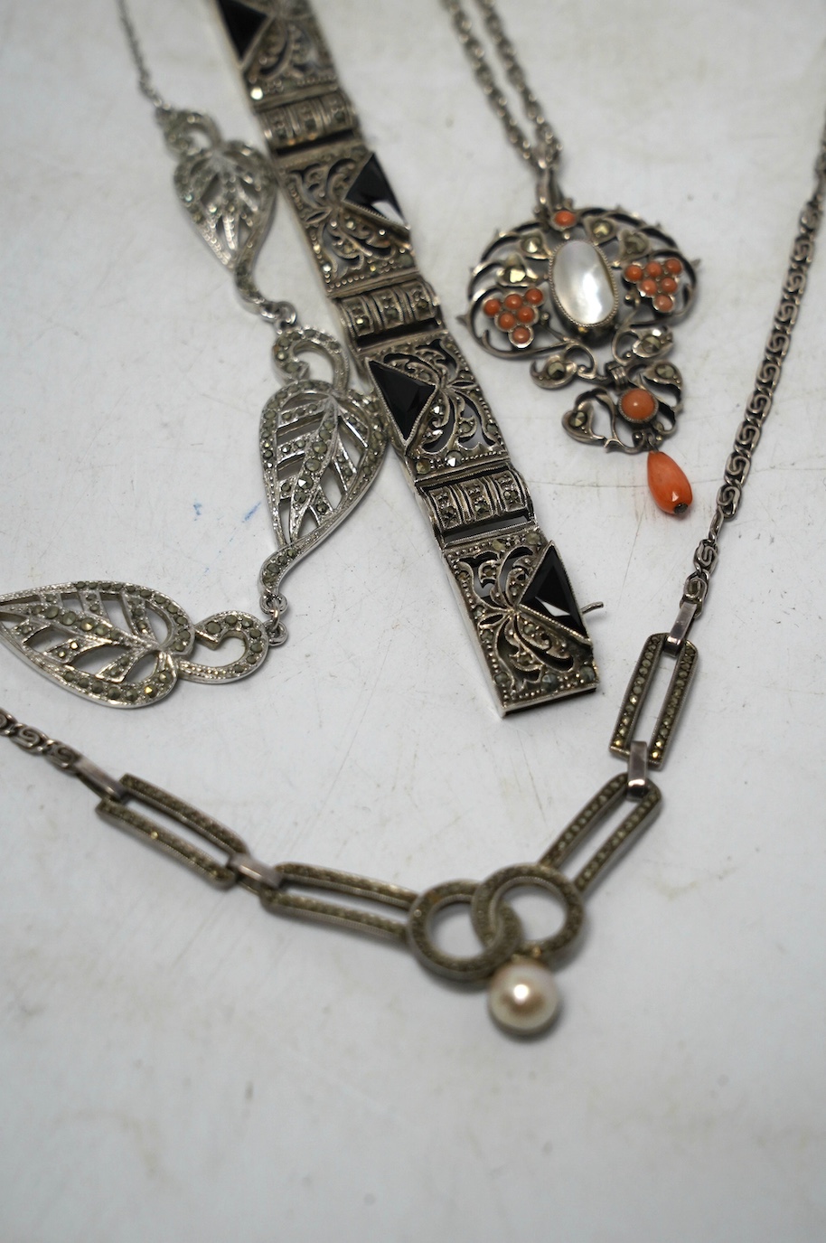 An early to mid 20th century white metal, mother of pearl and coral bead set drop pendant necklace, overall 60cm, together with two white metal and marcasite set necklaces, one stamped 925 and a German 935 marcasite and